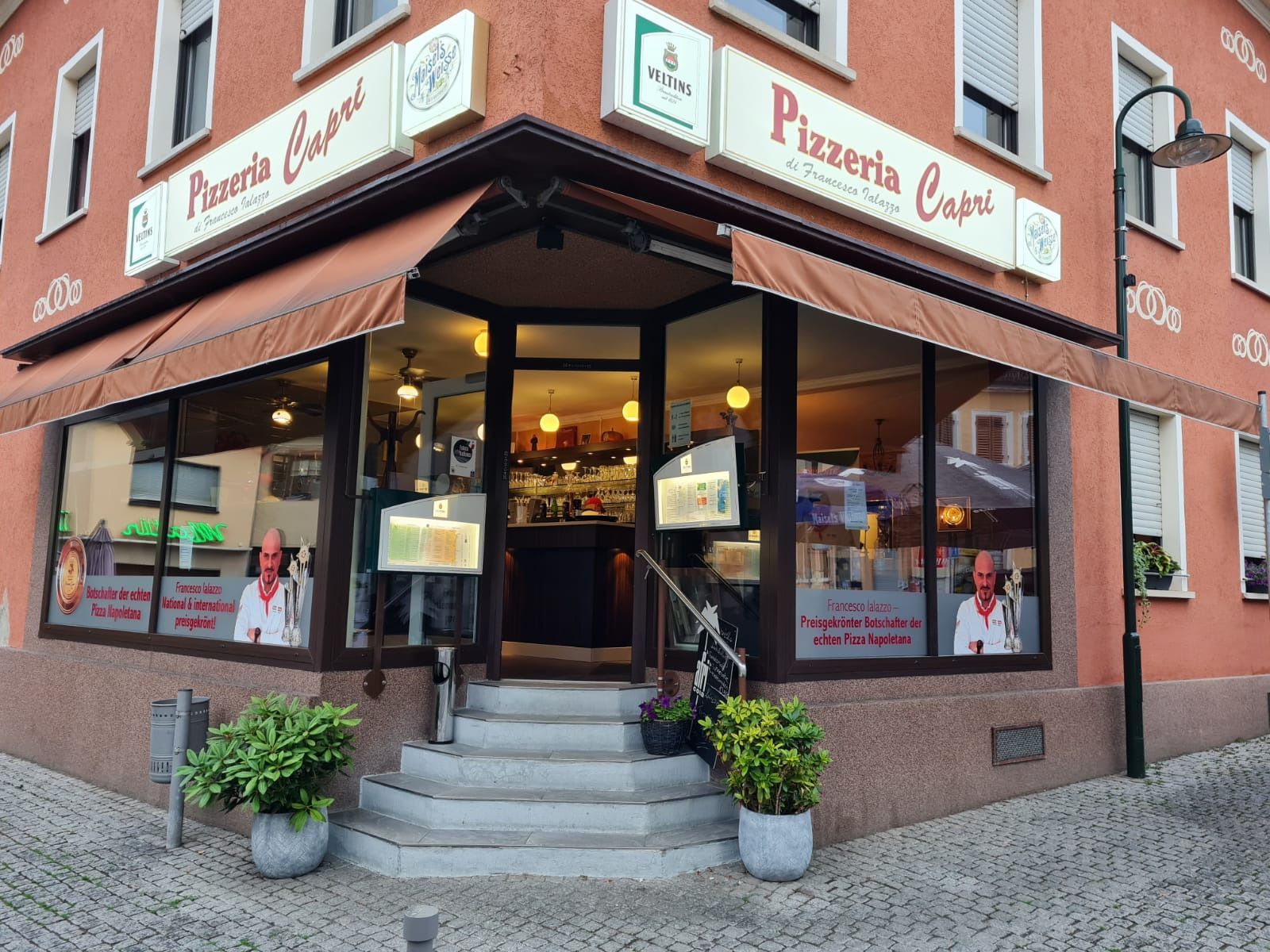 Eckeingang der Pizzeria Capri in Ingelheim mit den Leuchtschildern „Pizzeria Capri – di Francesco Ialazzo“